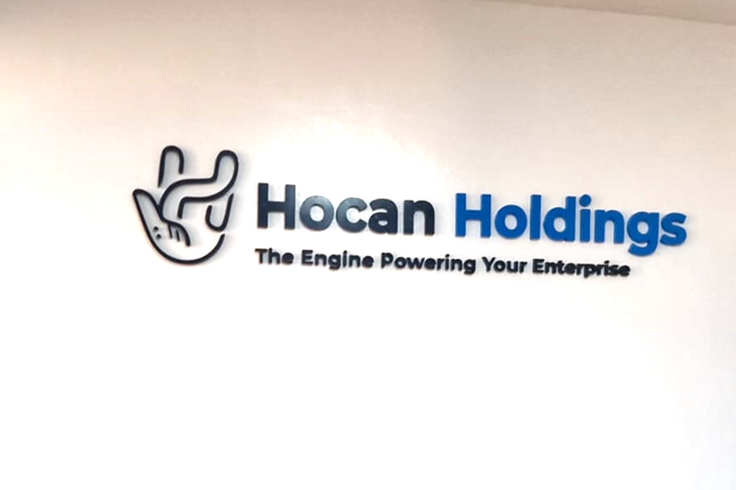 The Hocan Holdings logo and tagline mounted on the reception wall